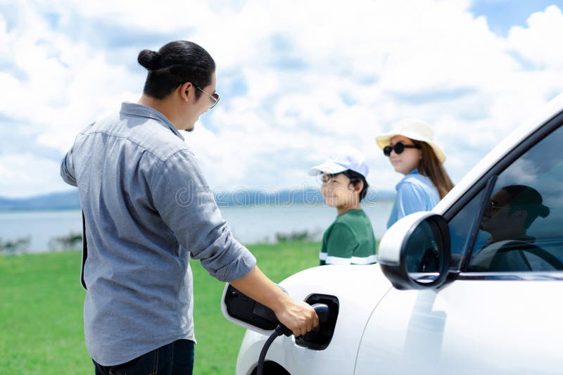 Concept of progressive happy family at green field, lake with electric vehicle.