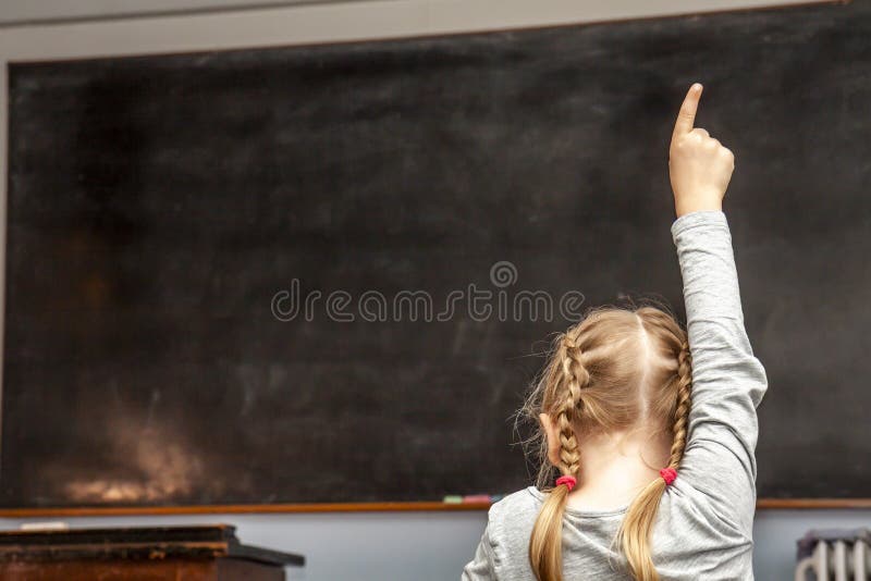 Concept of public primary school education with young girl raising her hand in the classroom royalty free stock photos Concept of public primary school education with young girl raising her hand in the classroom royalty free stock photos