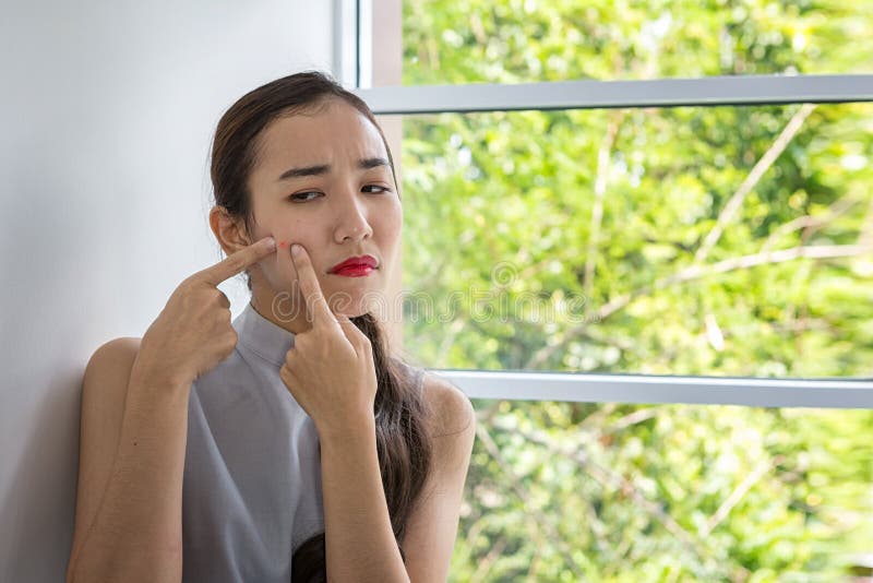 Concept for skin care and face problem. The girl is dismayed with acne on the face. Asian woman unhappy touching her skin royalty free stock photos Concept for skin care and face problem. The girl is dismayed with acne on the face. Asian woman unhappy touching her skin royalty free stock photos