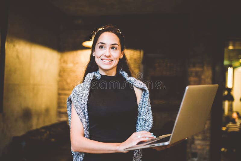 The concept of small business and technology. Young beautiful brunette businesswoman in black dress and gray sweater stands in cof stock images The concept of small business and technology. Young beautiful brunette businesswoman in black dress and gray sweater stands in cof stock images