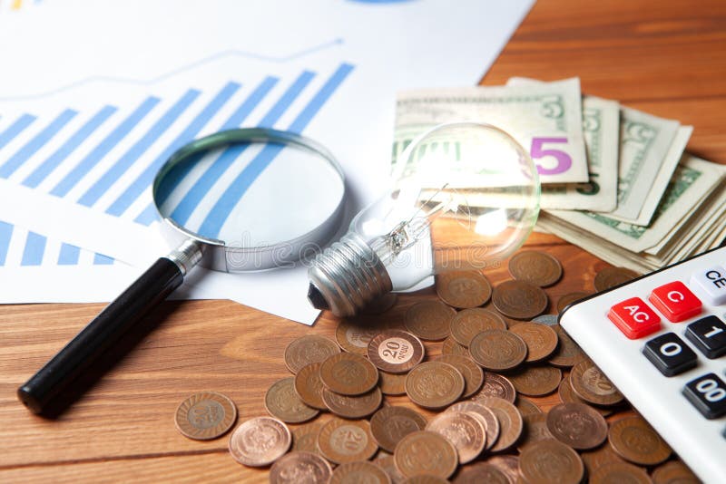 Concept of studying costs. coins next to calculator, magnifier and lamp stock image