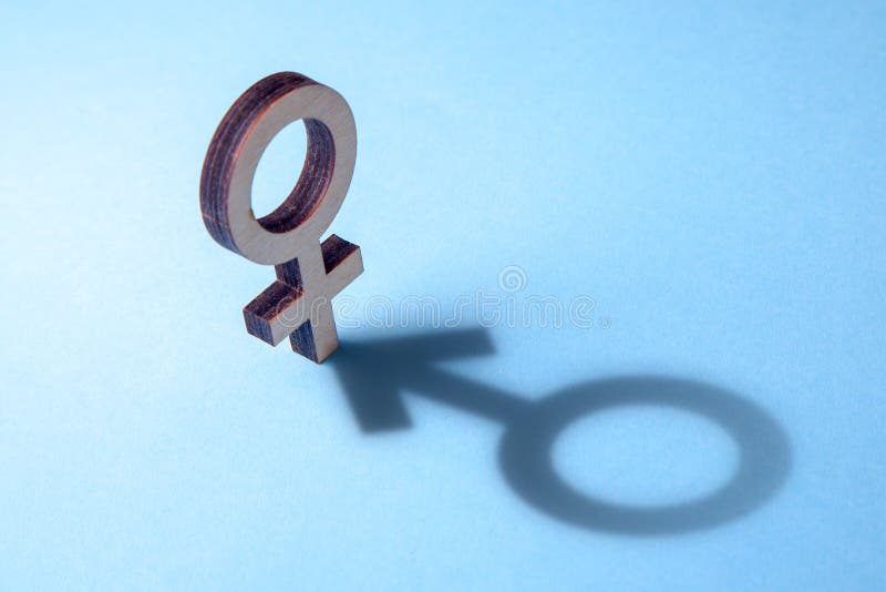 Concept of transvestite or bisexual. Tranender, woman feels like man. Shadow of woman`s gerner symbol in the form of symbol of man