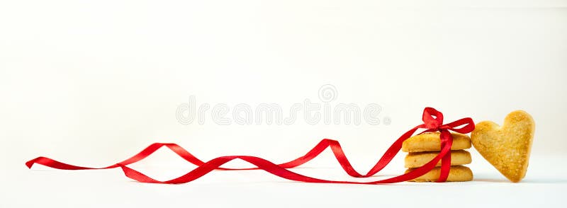 Concept Valentine`s Day. Cookies in the Shape of Hearts Tied with a Red Ribbon. Sweet Gift on Light Background. Banner. Copy Spac