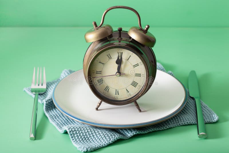 Concept of intermittent fasting, ketogenic diet, weight loss. fork and knife, alarmclock. Concept of intermittent fasting, ketogenic diet, weight loss. fork and knife, alarmclock