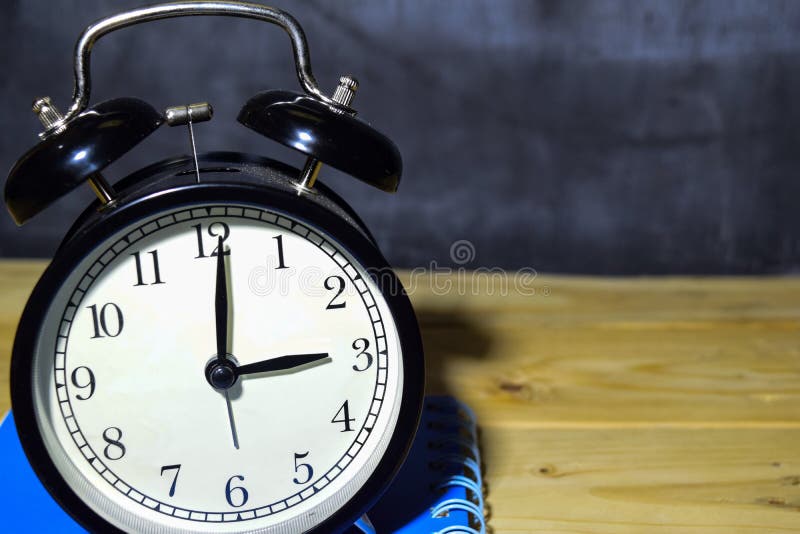 Concept vintage background black retro alarm clock on 15.00 pm or 03.00 am and blue book