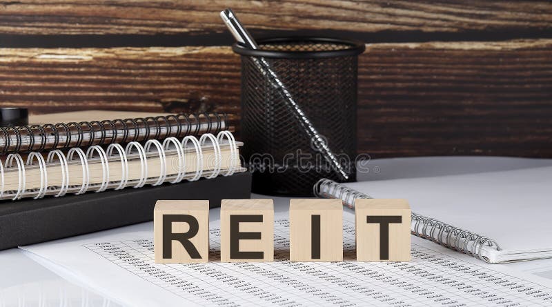 Concept word REIT on the wooden blocks on the gray background from green flower and chart stock images