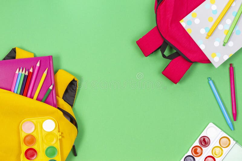 Concept înapoi la școală. rucsacuri galbene și roz, cu cărți și notebook-uri de tip școlar pe fond verde deschis. royalty free stock photo