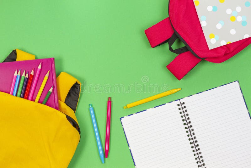 Concept înapoi la școală. rucsacuri galbene și roz, cu cărți și notebook-uri de tip școlar pe fond verde deschis. stock photo