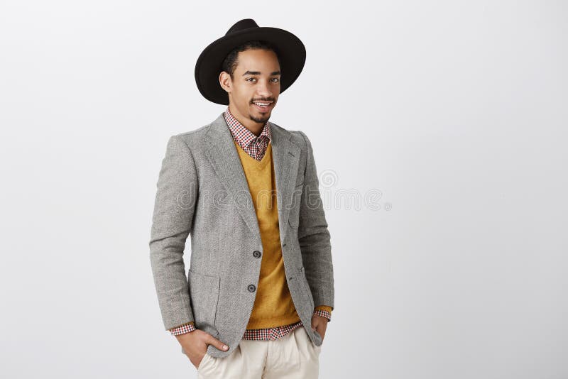 Concepteur créatif discutant le défilé de mode Modèle masculin à la peau foncée beau dans la veste et le chapeau élégants, moitié image libre de droits Concepteur créatif discutant le défilé de mode Modèle masculin à la peau foncée beau dans la veste et le chapeau élégants, moitié image libre de droits