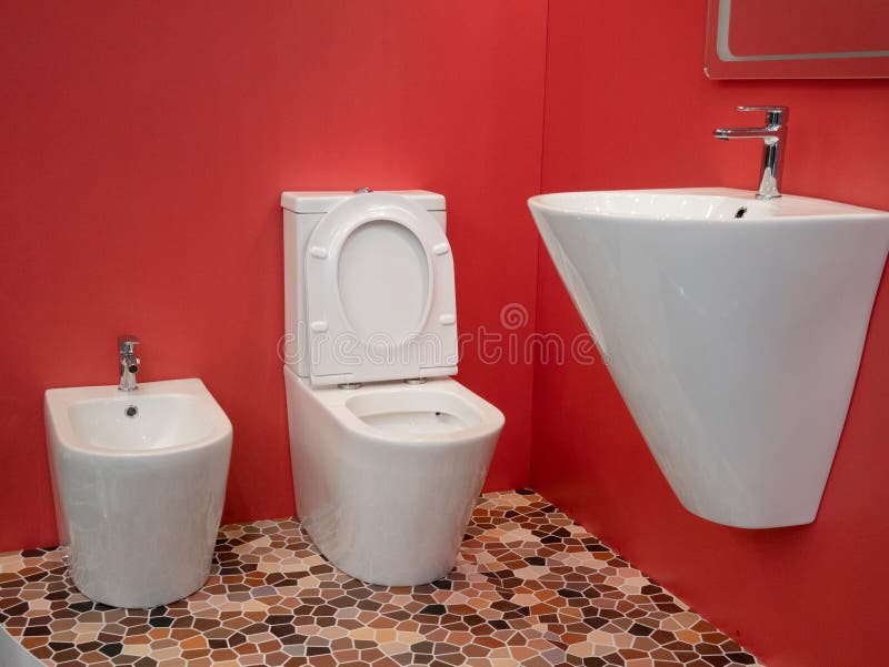 Conception int?rieure de salle de bains ? la maison moderne avec le lavabo blanc, la toilette, le bidet et les murs rouges vifs image libre de droits Conception int?rieure de salle de bains ? la maison moderne avec le lavabo blanc, la toilette, le bidet et les murs rouges vifs image libre de droits