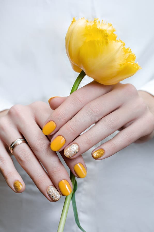 Conception jaune de clou Main femelle tenant la tulipe jaune photographie stock Conception jaune de clou Main femelle tenant la tulipe jaune photographie stock