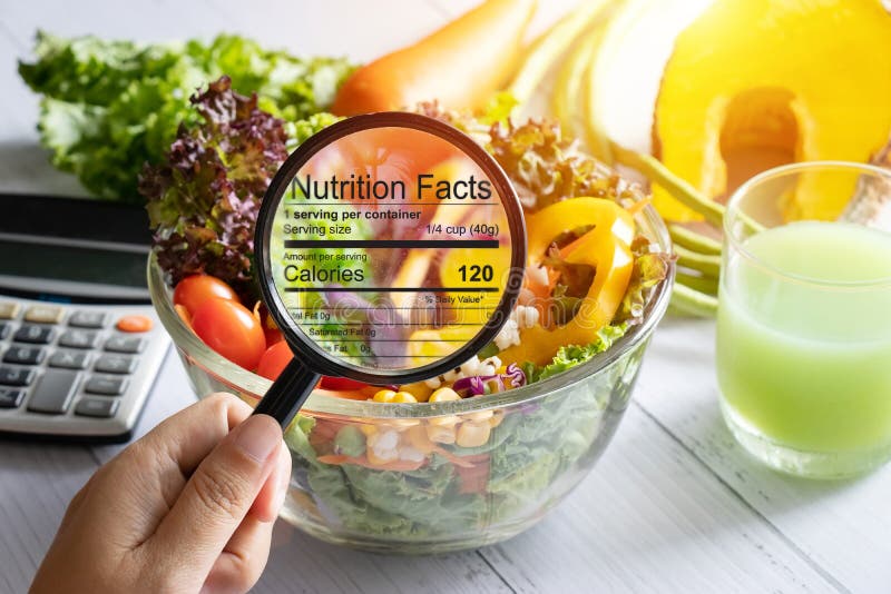 Nutritional information concept. hand use the magnifying glass to zoom in to see the details of the nutrition facts from food , salad bowl. Nutritional information concept. hand use the magnifying glass to zoom in to see the details of the nutrition facts from food , salad bowl