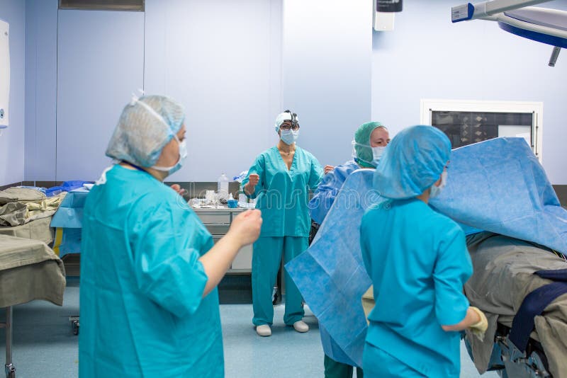 Concepto de la cirugía, de la medicina y de la gente - grupo de cirujanos en sala de operaciones en el hospital que hablan y que foto de archivo libre de regalías Concepto de la cirugía, de la medicina y de la gente - grupo de cirujanos en sala de operaciones en el hospital que hablan y que foto de archivo libre de regalías