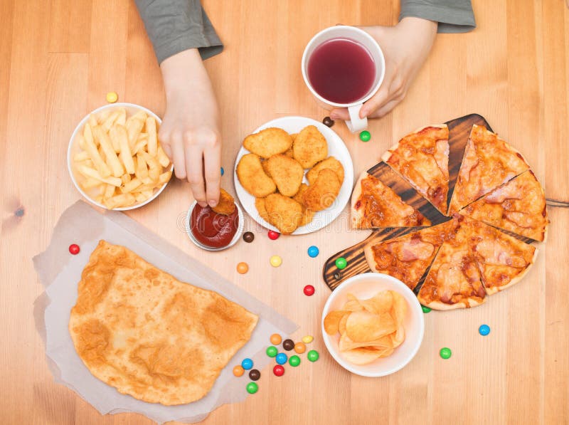 Concepto de la comida basura de los alimentos de preparación rápida Muchacho adolescente que come las pepitas, pizza, ji foto de archivo libre de regalías Concepto de la comida basura de los alimentos de preparación rápida Muchacho adolescente que come las pepitas, pizza, ji foto de archivo libre de regalías