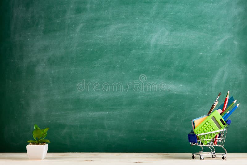 Concepto de la educación - fuentes de escuela en un carro de la compra en el escritorio en el auditorio, fondo de la pizarra imagenes de archivo Concepto de la educación - fuentes de escuela en un carro de la compra en el escritorio en el auditorio, fondo de la pizarra imagenes de archivo