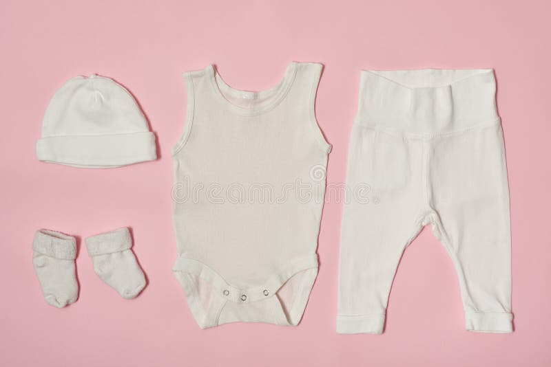 Concepto de la moda del bebé en un fondo rosado Casquillo, mono, pantalones y calcetines foto de archivo libre de regalías Concepto de la moda del bebé en un fondo rosado Casquillo, mono, pantalones y calcetines foto de archivo libre de regalías