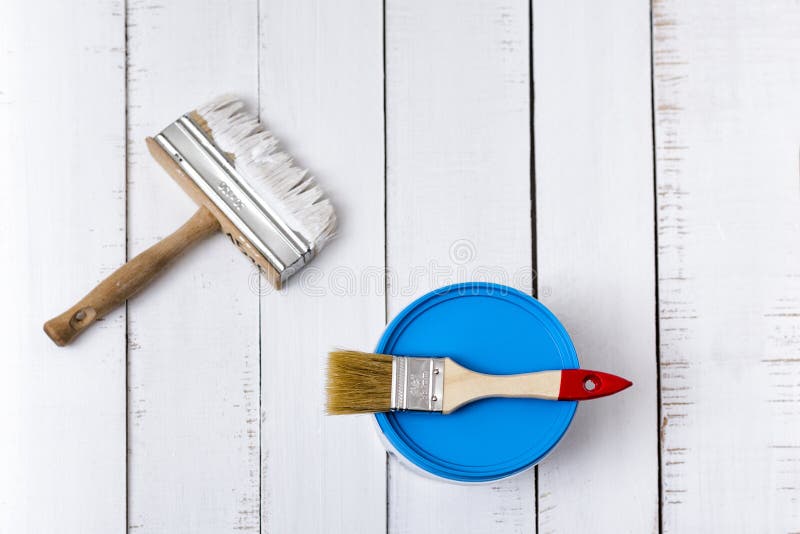 Concepto de la renovación de la casa Cubo del paintbrushe dos y de la pintura en un fondo de los tablones de madera blancos, lame foto de archivo Concepto de la renovación de la casa Cubo del paintbrushe dos y de la pintura en un fondo de los tablones de madera blancos, lame foto de archivo