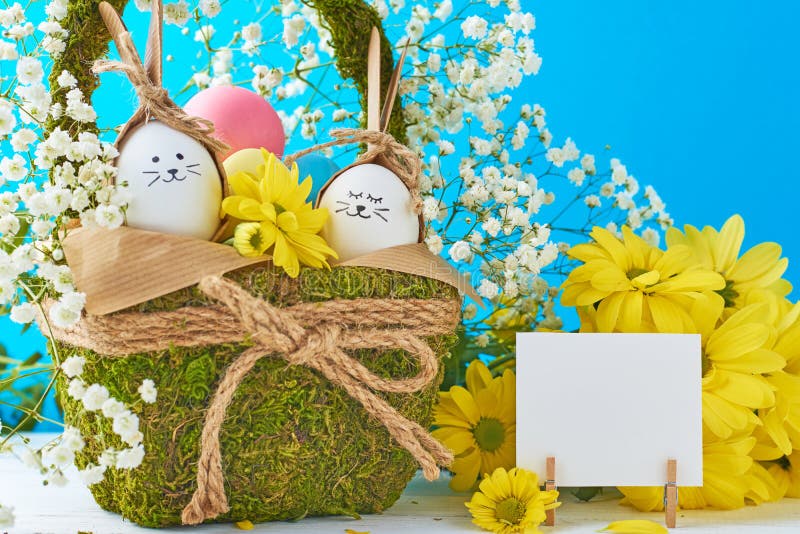 Concepto de Pascua Huevos en la cesta adornada con las flores en un fondo azul foto de archivo libre de regalías Concepto de Pascua Huevos en la cesta adornada con las flores en un fondo azul foto de archivo libre de regalías