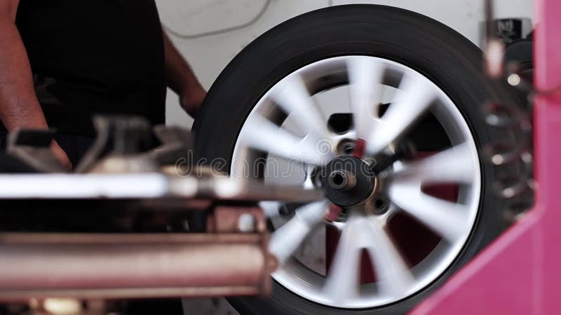 Concepto de sustitución de neumáticos. mecánico trabajando con rueda en el garaje. mantenimiento y servicio de coches a cámara baj almacen de video