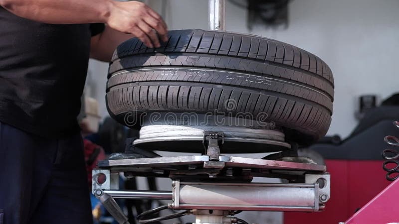 Concepto de sustitución de neumáticos. mecánico trabajando con rueda en el garaje. mantenimiento y servicio de coches a cámara baj almacen de video