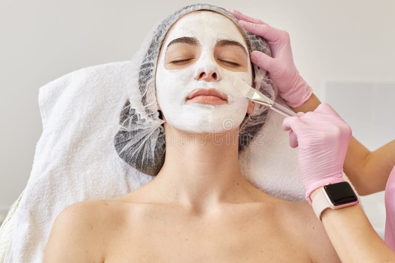 Concepto del cuidado del balneario y de piel Mujer joven con la máscara facial en salón de belleza, cosmetologist que usa el cepi imágenes de archivo libres de regalías Concepto del cuidado del balneario y de piel Mujer joven con la máscara facial en salón de belleza, cosmetologist que usa el cepi imágenes de archivo libres de regalías