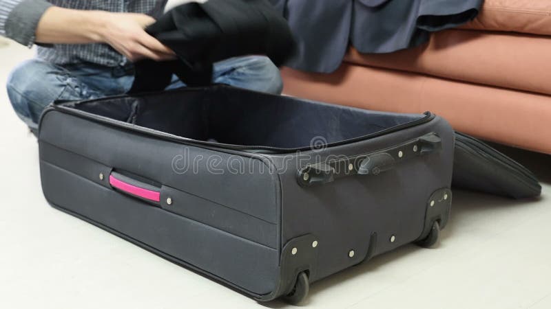 Concepto del viaje, del equipaje y de la gente - sirva la ropa del embalaje en bolso del viaje