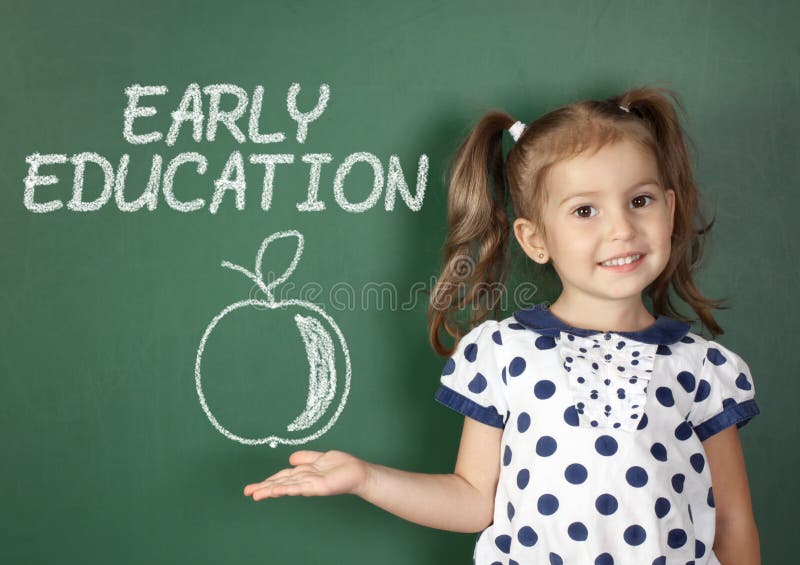 Concepto temprano de la educación, muchacha del niño cerca de la pizarra de la escuela foto de archivo Concepto temprano de la educación, muchacha del niño cerca de la pizarra de la escuela foto de archivo