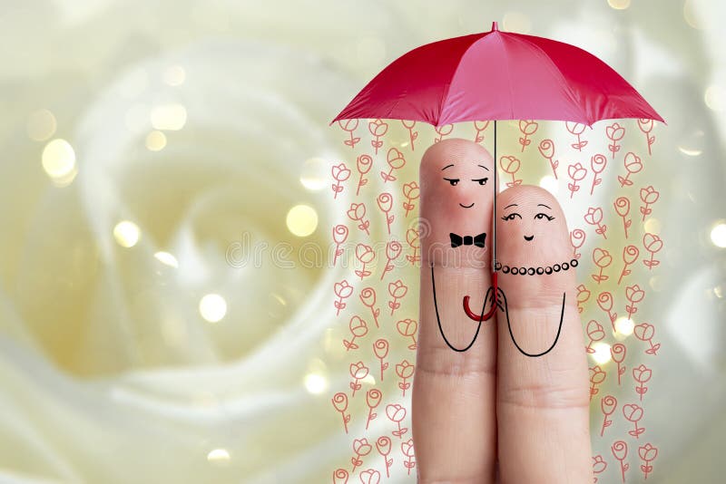 Conceptual finger art. Lovers are embracing and holding umbrella with falling flowers. Stock Image