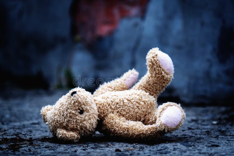 Conceptual photography: war, death and lost childhood. Conceptual picture of a children`s toy teddy bear on a background of broke