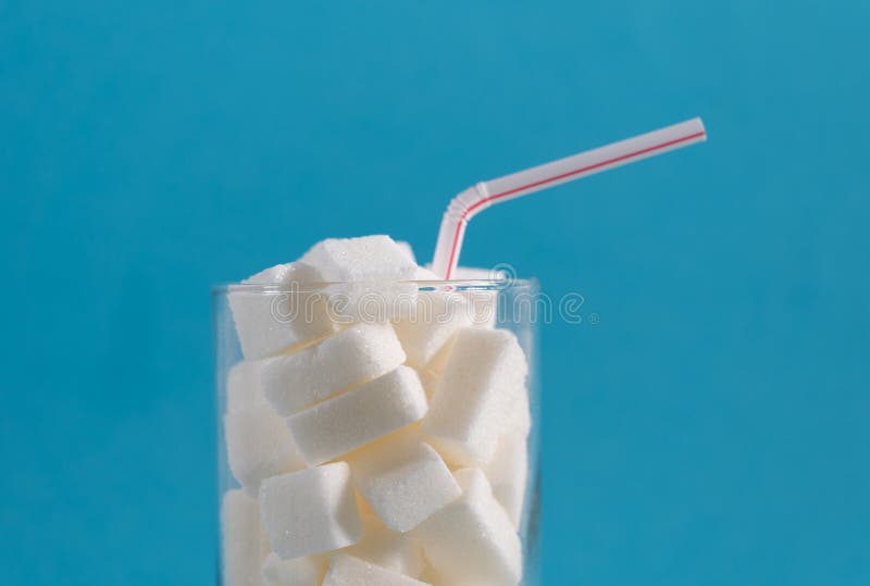 Conceptual still life image of glass full of sugar cubes and straw in excess of calories in soft drinks