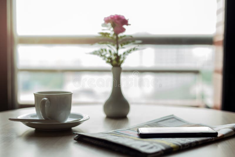 Conceptuele kop van koffie met krant en celtelefoon op houten stock afbeelding Conceptuele kop van koffie met krant en celtelefoon op houten stock afbeelding
