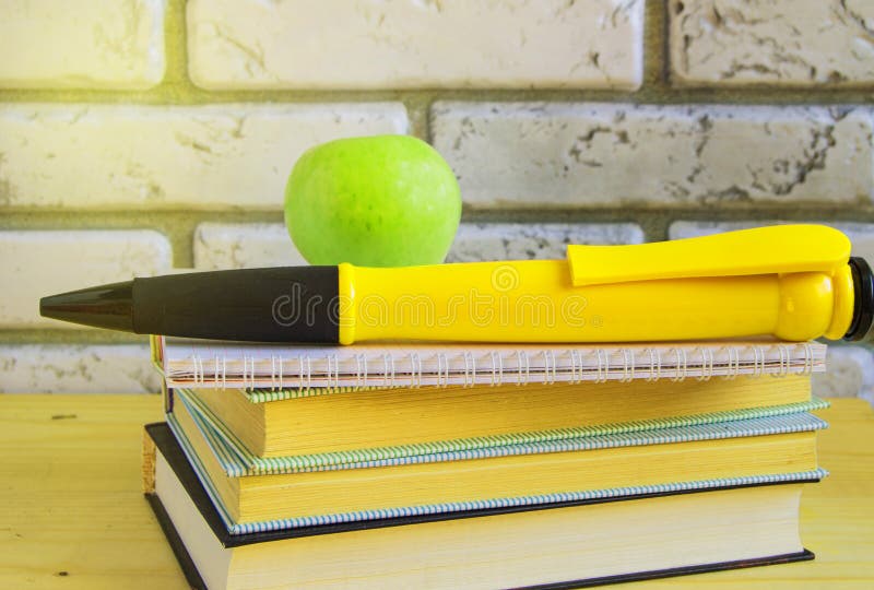 Conceptul de zi a profesorilor și înapoi la școală, mere verzi, creion suvenos mare pe cărți și caiete lumina soarelui royalty free stock image