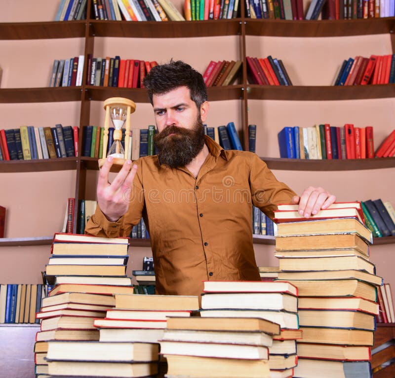 Concetto del bibliotecario L'insegnante, scienziato con la barba sta alla tavola con i libri, defocused Uomo sui supporti premuro fotografia stock Concetto del bibliotecario L'insegnante, scienziato con la barba sta alla tavola con i libri, defocused Uomo sui supporti premuro fotografia stock