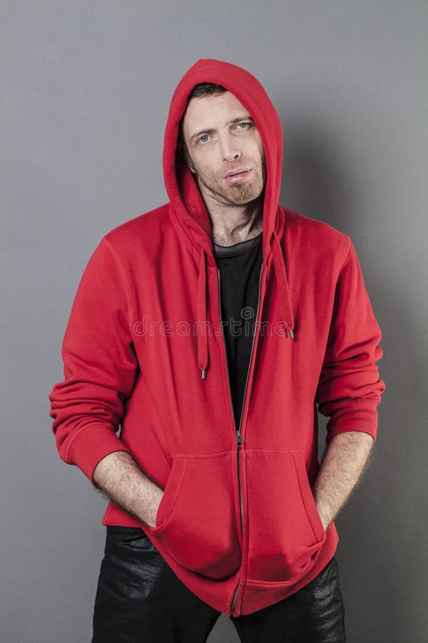 40s man wearing red teen sportswear and hoodie on,looking depressed and lost with two hands in both pockets of hooded sweater. 40s man wearing red teen sportswear and hoodie on,looking depressed and lost with two hands in both pockets of hooded sweater