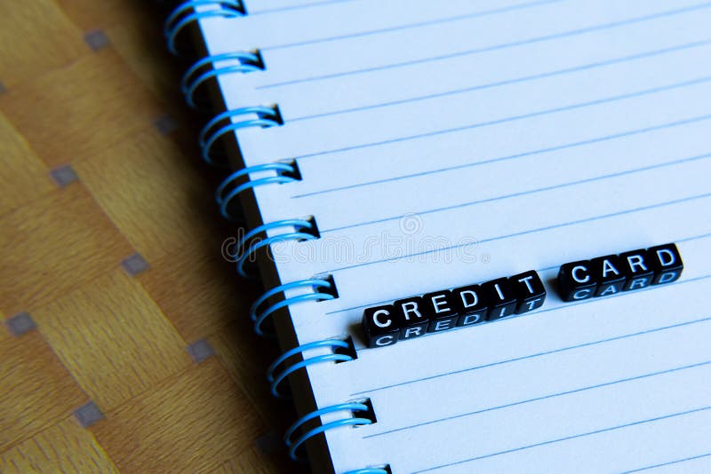 Concetto della carta di credito sui cubi di legno con i libri nel fondo fotografia stock Concetto della carta di credito sui cubi di legno con i libri nel fondo fotografia stock