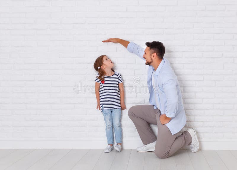 Concetto della famiglia il padre misura la crescita del bambino nel da fotografia stock libera da diritti Concetto della famiglia il padre misura la crescita del bambino nel da fotografia stock libera da diritti