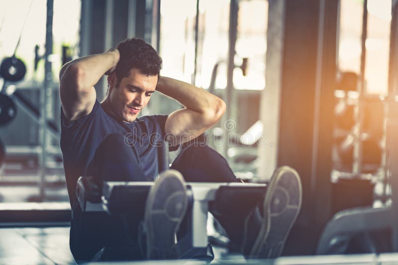 Concetto della palestra, forma fisica, sport, sano, stile di vita Il giovane misura si siede aumenta sulla macchina in abiti spor immagini stock Concetto della palestra, forma fisica, sport, sano, stile di vita Il giovane misura si siede aumenta sulla macchina in abiti spor immagini stock