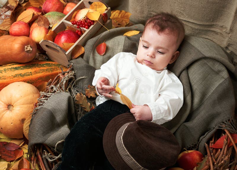 Concetto di autunno - la bugia del ragazzo del bambino su giallo va con i frutti e vegatbles, mele rosse e zucche immagini stock Concetto di autunno - la bugia del ragazzo del bambino su giallo va con i frutti e vegatbles, mele rosse e zucche immagini stock