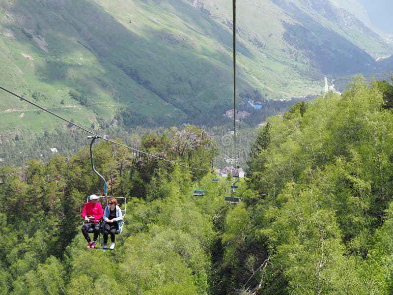 concetto di corsa Accoppi delle viandanti o i turisti godono del giro dell'ascensore di sci della seggiovia e di bello paesaggio fotografia stock libera da diritti concetto di corsa Accoppi delle viandanti o i turisti godono del giro dell'ascensore di sci della seggiovia e di bello paesaggio fotografia stock libera da diritti