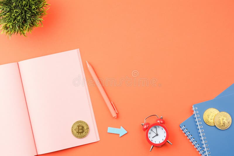 Concetto di desktop per notebook aperto. Taccuino aperto rosa con pianta bitcoin verde foglie rosso allarme orologio blu spirale e penna. sulla vista superiore di sfondo isolata arancione.
