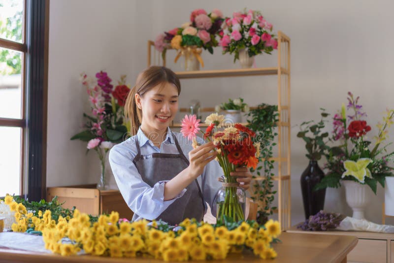 Concetto di fioraio femminile gerberas colorato organizzato in vaso di vetro per cliente presso un negozio di fiori immagini stock libere da diritti