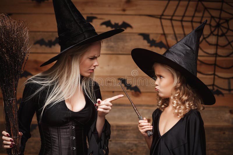Concetto di Halloween - la madre stressante della strega che insegna a sua figlia in strega costumes la celebrazione del Hallowee fotografia stock libera da diritti Concetto di Halloween - la madre stressante della strega che insegna a sua figlia in strega costumes la celebrazione del Hallowee fotografia stock libera da diritti