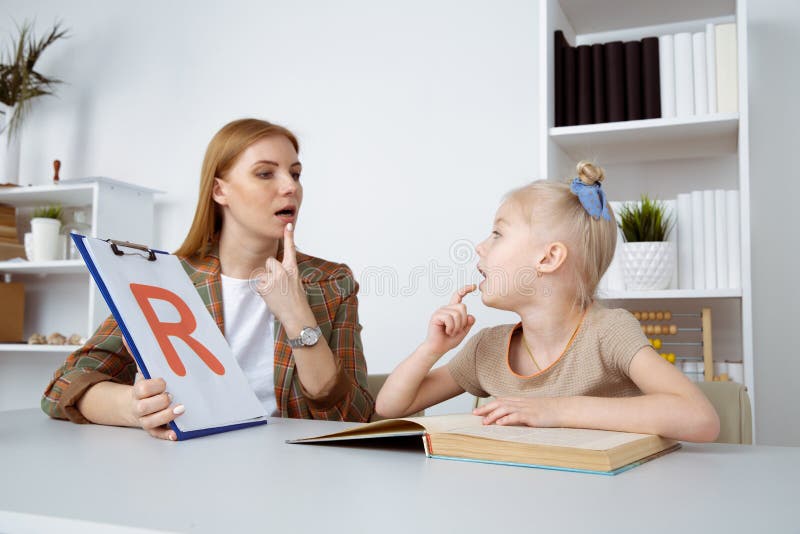 Speech therapy concept. Patient kid with female therapist training pronunciation. Speech therapy concept. Patient kid with female therapist training pronunciation