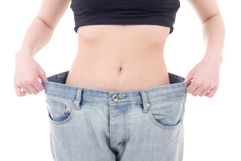 Concetto di perdita di peso - donna esile in grandi jeans isolati su bianco fotografie stock Concetto di perdita di peso - donna esile in grandi jeans isolati su bianco fotografie stock