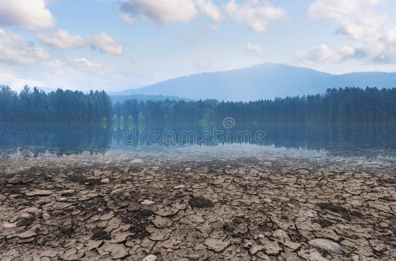 Concetto di riscaldamento globale e del mutamento climatico Lago asciutto e terra di siccità con la foresta e cielo blu con il pa immagini stock libere da diritti Concetto di riscaldamento globale e del mutamento climatico Lago asciutto e terra di siccità con la foresta e cielo blu con il pa immagini stock libere da diritti
