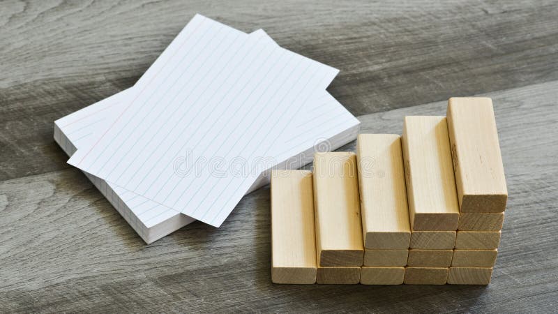 Business / Education Challenge Concept - Blank Index Cards With Stairway Upwards Of Building Blocks Over Dark Grey Wooden Background. Business / Education Challenge Concept - Blank Index Cards With Stairway Upwards Of Building Blocks Over Dark Grey Wooden Background