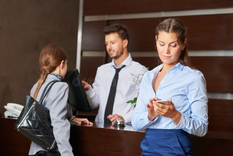 Concierge στους εξυπηρετώντας φιλοξενουμένους υποδοχής ξενοδοχείων στοκ φωτογραφία με δικαίωμα ελεύθερης χρήσης Concierge στους εξυπηρετώντας φιλοξενουμένους υποδοχής ξενοδοχείων στοκ φωτογραφία με δικαίωμα ελεύθερης χρήσης
