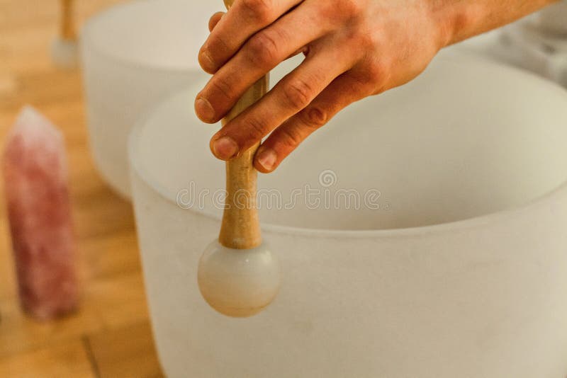 Man playing crystal bowls as part of a meditative concert, with Rose Quartz crystal. Man playing crystal bowls as part of a meditative concert, with Rose Quartz crystal