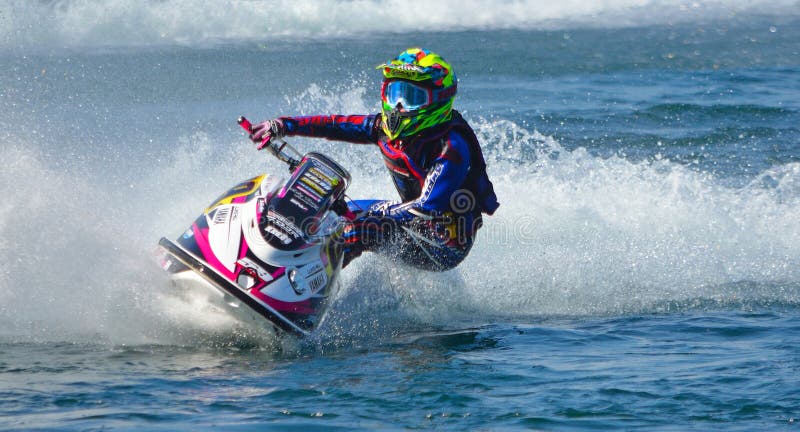 Concorrente de Jet Ski que encurrala na velocidade que cria no lote do pulverizador foto de stock Concorrente de Jet Ski que encurrala na velocidade que cria no lote do pulverizador foto de stock