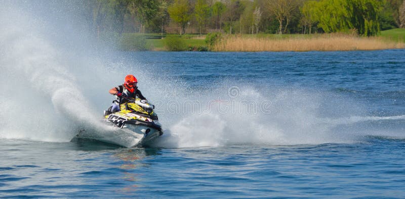 Concorrente de Jet Ski que encurrala na velocidade que cria no lote do pulverizador fotografia de stock Concorrente de Jet Ski que encurrala na velocidade que cria no lote do pulverizador fotografia de stock